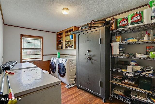 clothes washing area featuring crown molding, washer and dryer, a textured ceiling, and light hardwood / wood-style floors