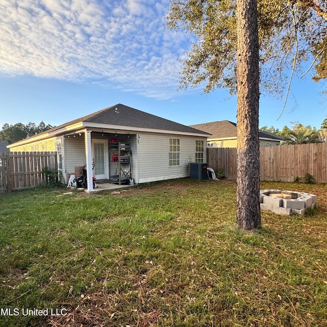 rear view of property featuring a lawn, an outdoor fire pit, a patio, and central AC