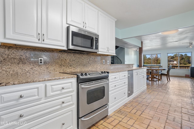 kitchen featuring light stone countertops, stainless steel appliances, wine cooler, decorative backsplash, and white cabinets