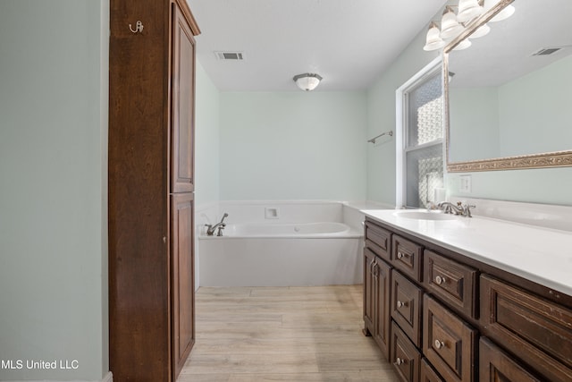 bathroom with a washtub, vanity, and hardwood / wood-style flooring