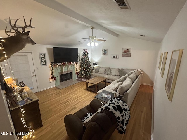 living room featuring vaulted ceiling with beams, a premium fireplace, ceiling fan, and hardwood / wood-style flooring