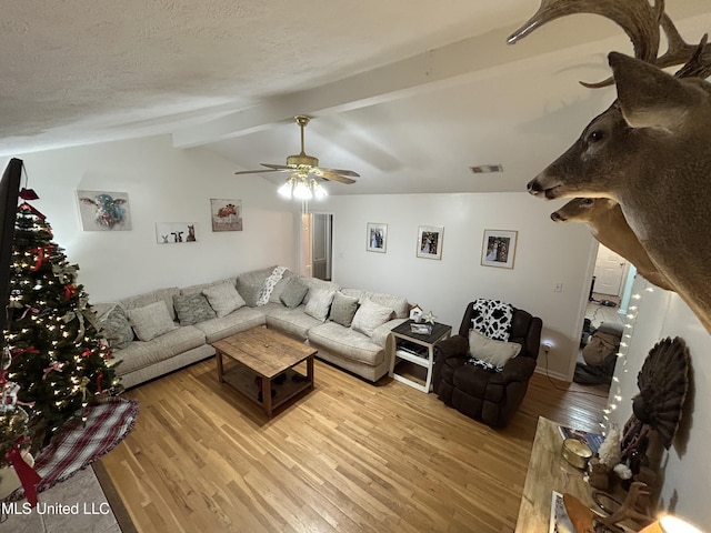 living room with vaulted ceiling with beams, ceiling fan, a textured ceiling, and light wood-type flooring