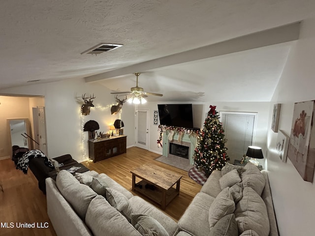 living room with lofted ceiling with beams, light hardwood / wood-style flooring, ceiling fan, and a premium fireplace