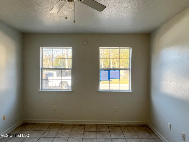 tiled empty room with ceiling fan and a textured ceiling