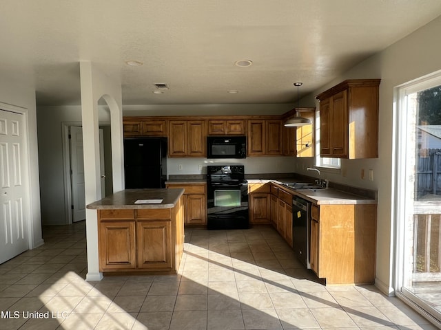 kitchen featuring sink, light tile patterned floors, black appliances, and decorative light fixtures