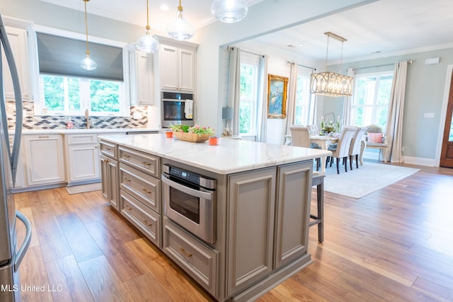 kitchen with appliances with stainless steel finishes, light wood-style flooring, and crown molding