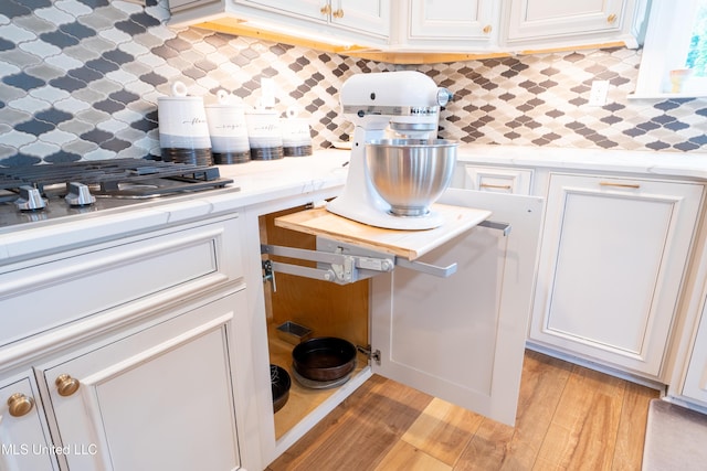 kitchen with light wood-type flooring, white cabinets, and decorative backsplash