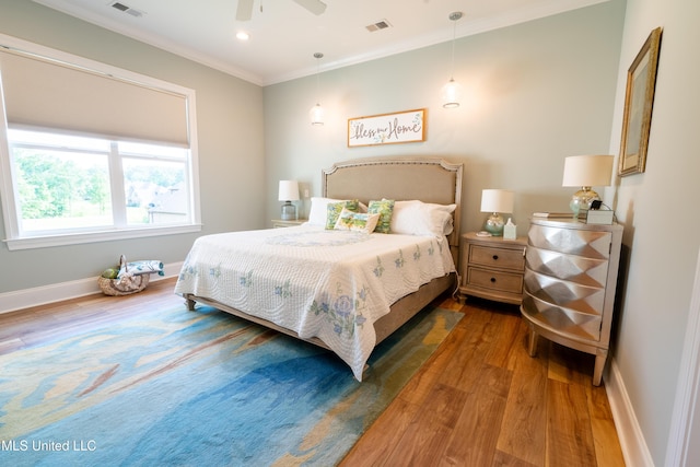 bedroom with baseboards, visible vents, crown molding, and wood finished floors