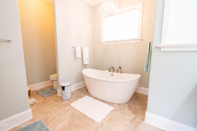 full bathroom featuring a chandelier, a freestanding tub, toilet, baseboards, and tile patterned floors