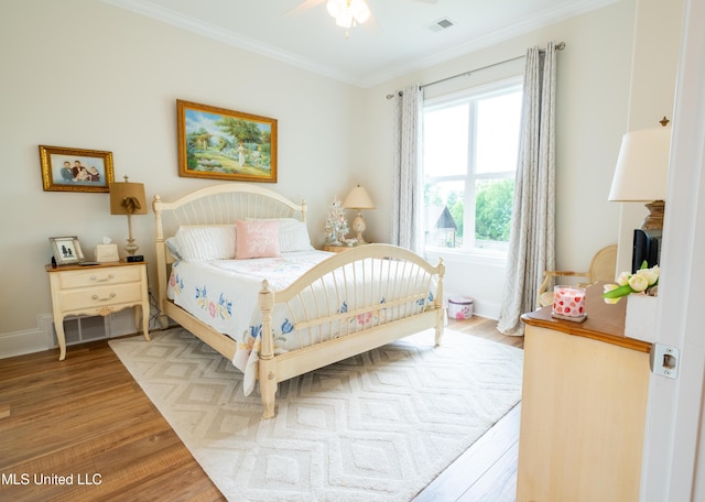 bedroom with wood finished floors, a ceiling fan, visible vents, baseboards, and ornamental molding