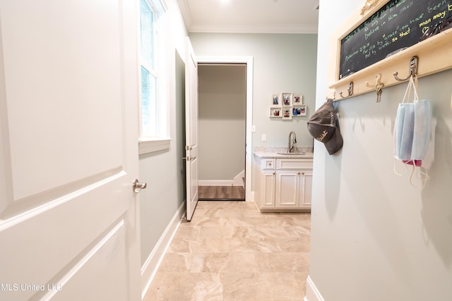 mudroom with marble finish floor, baseboards, ornamental molding, and a sink