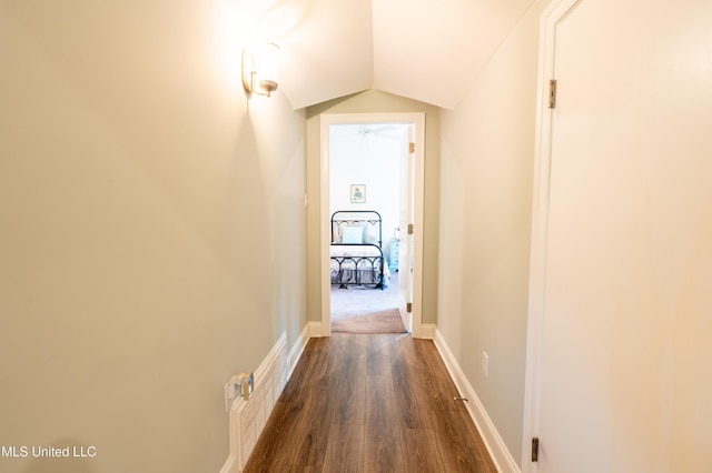 hallway with dark wood-style floors, vaulted ceiling, and baseboards