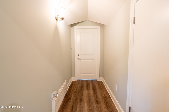 hall featuring baseboards, vaulted ceiling, and dark wood-style flooring