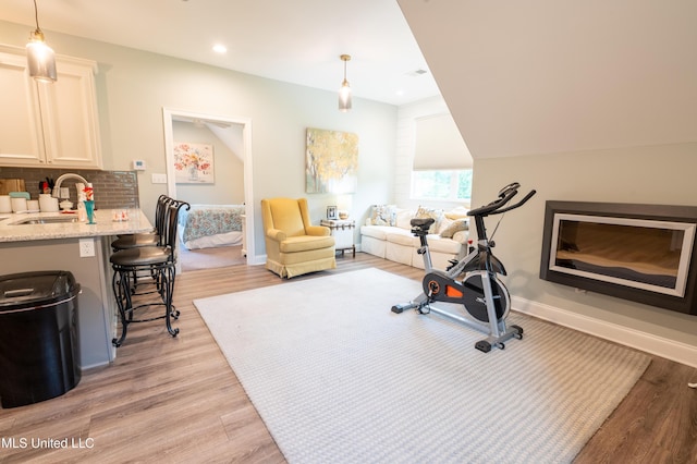 workout room with light wood-style flooring, baseboards, and a sink