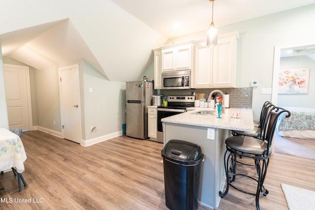 kitchen with light wood-style flooring, stainless steel appliances, a breakfast bar, a sink, and decorative backsplash