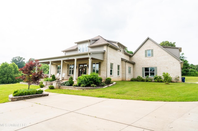 view of front of home with covered porch, roof with shingles, and a front lawn