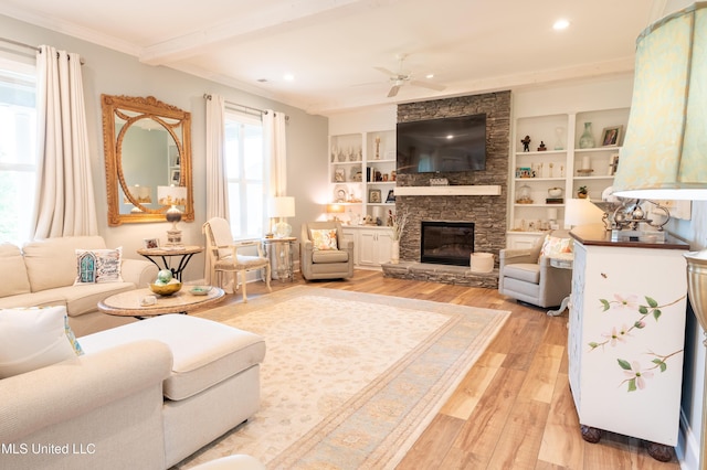 living area with a fireplace, a ceiling fan, light wood-style floors, ornamental molding, and beamed ceiling