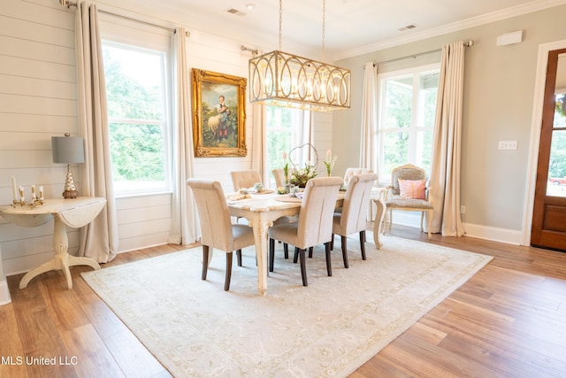 dining area featuring light wood-style floors, plenty of natural light, visible vents, and crown molding