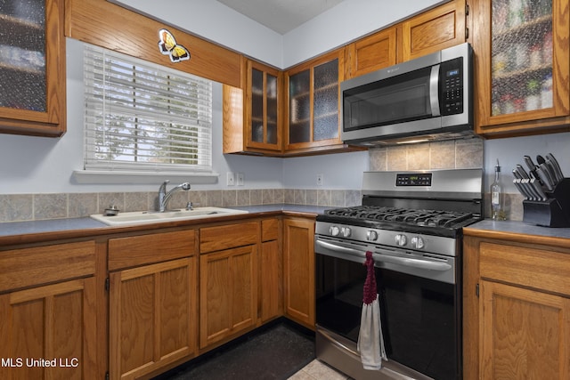 12509 Ponce De Leon Dr, Ocean Springs, MS 39564 - kitchen featuring a sink, brown cabinetry, glass insert cabinets, and appliances with stainless steel finishes