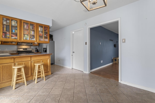 12509 Ponce De Leon Dr, Ocean Springs, MS 39564 - kitchen with glass insert cabinets, light tile patterned floors, baseboards, a sink, and appliances with stainless steel finishes