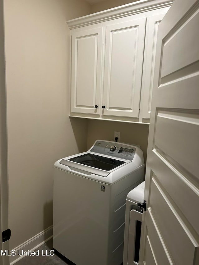 clothes washing area with cabinets and separate washer and dryer