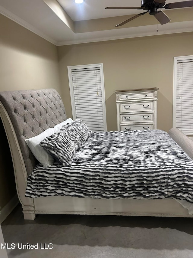 bedroom with ceiling fan, crown molding, a tray ceiling, and dark carpet