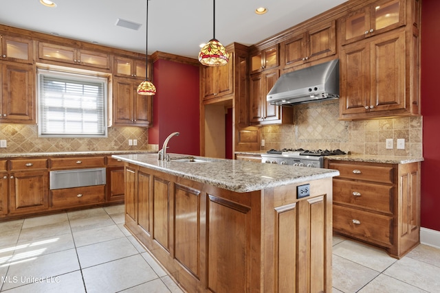 1529 Magnolia St Unit 15, Gulfport, MS 39507 - kitchen featuring under cabinet range hood, a warming drawer, a sink, light tile patterned floors, and brown cabinetry