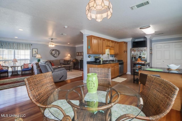 dining room with ornamental molding, wood-type flooring, sink, and ceiling fan