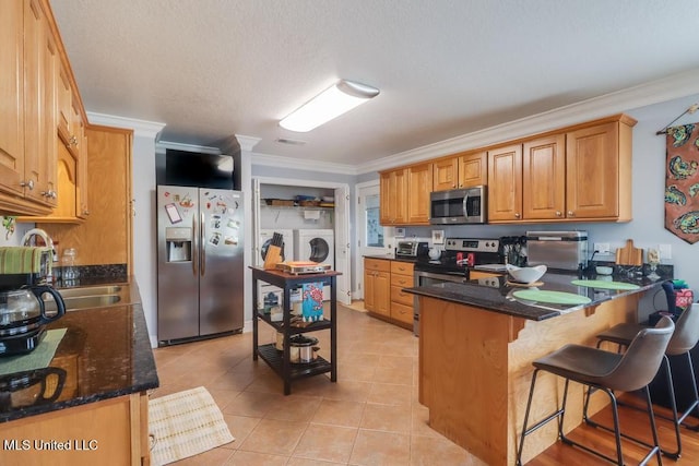 kitchen featuring washing machine and clothes dryer, appliances with stainless steel finishes, kitchen peninsula, and ornamental molding