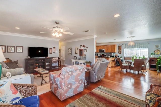 living room featuring hardwood / wood-style flooring, ornamental molding, ceiling fan, and a textured ceiling