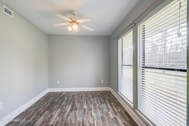 empty room with ceiling fan, wood finished floors, visible vents, and baseboards