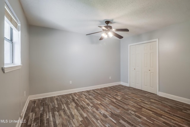 unfurnished bedroom with ceiling fan, baseboards, wood finished floors, a closet, and a textured ceiling