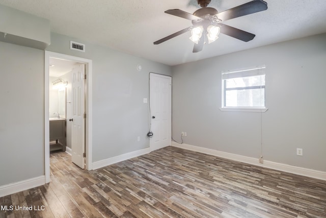 unfurnished bedroom featuring visible vents, ceiling fan, baseboards, wood finished floors, and a textured ceiling