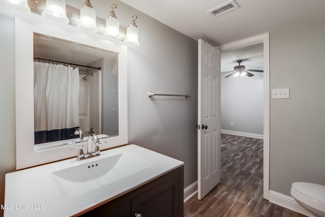 bathroom featuring visible vents, ceiling fan, toilet, wood finished floors, and vanity