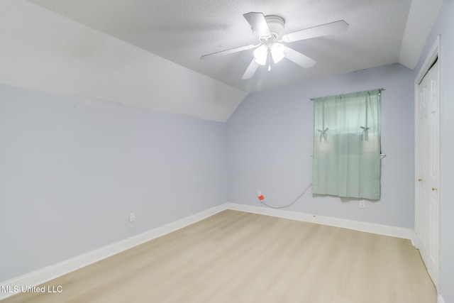 bonus room with vaulted ceiling, wood finished floors, baseboards, and a textured ceiling