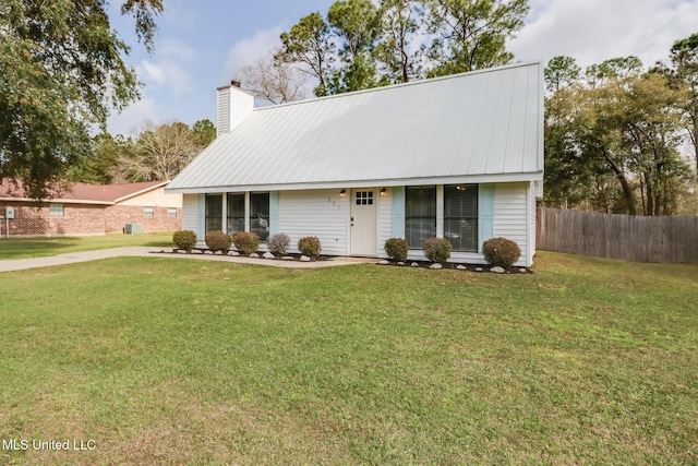 view of front of house featuring metal roof, a chimney, a front lawn, and fence