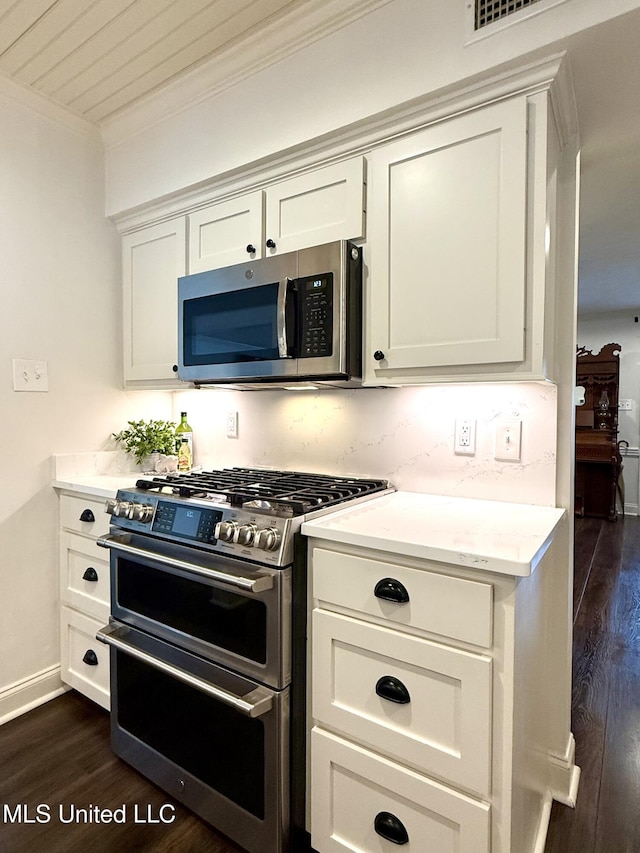 kitchen featuring appliances with stainless steel finishes, crown molding, dark wood finished floors, light countertops, and white cabinets