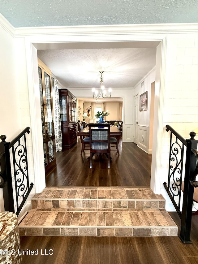 dining area with dark wood-style floors, a chandelier, and crown molding