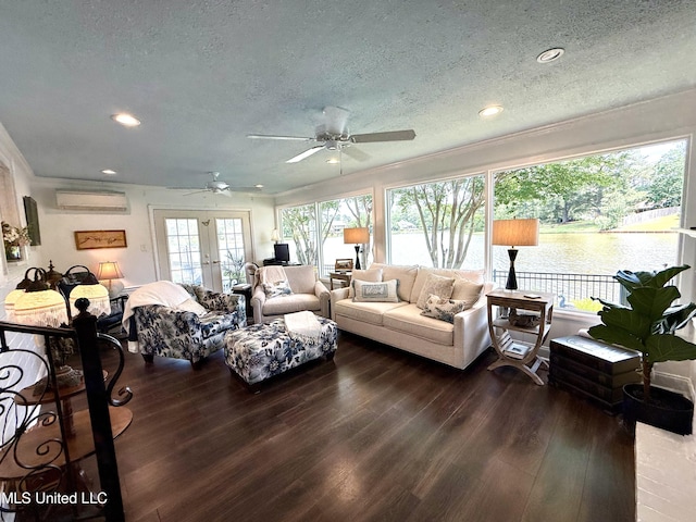 living area featuring a textured ceiling, an AC wall unit, wood finished floors, a ceiling fan, and french doors