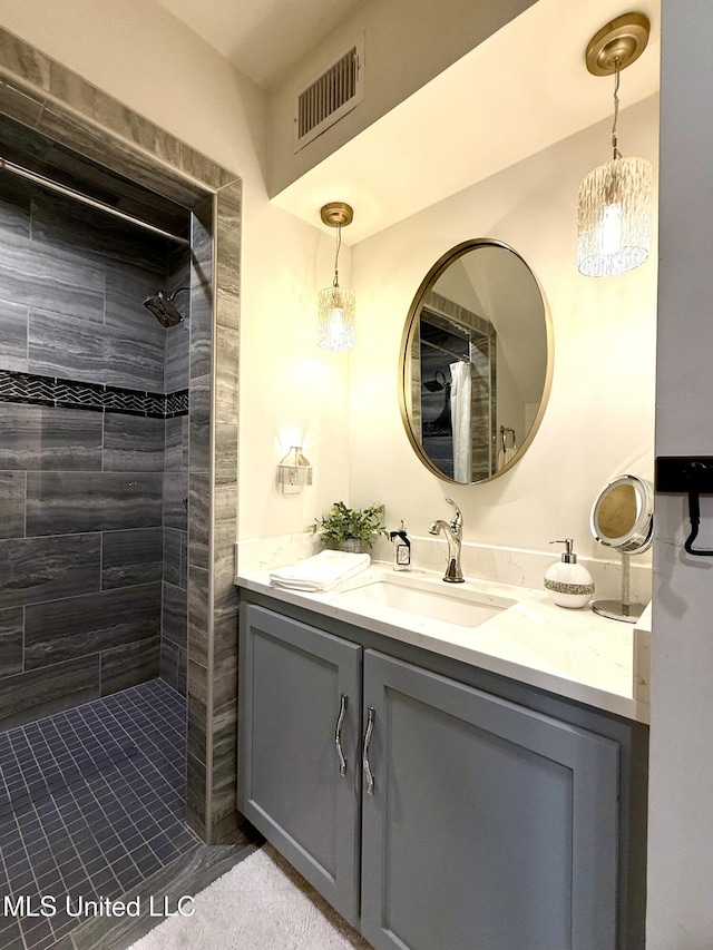 full bathroom with tiled shower and vanity