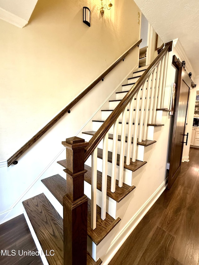 stairway featuring wood finished floors, baseboards, and crown molding