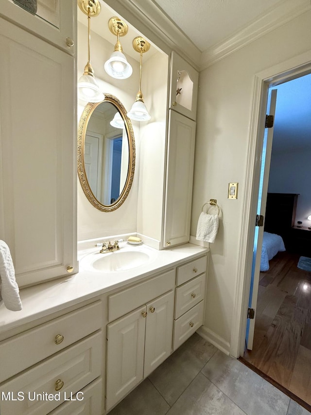 ensuite bathroom featuring ornamental molding, vanity, tile patterned floors, and baseboards