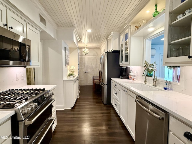 kitchen with appliances with stainless steel finishes, a sink, wooden ceiling, white cabinetry, and ornamental molding
