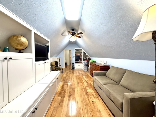 living area featuring lofted ceiling, light wood finished floors, ceiling fan, and built in shelves