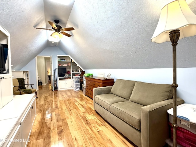bedroom with vaulted ceiling, light wood-style flooring, a ceiling fan, and a textured ceiling