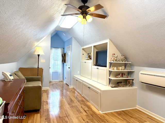 living area featuring a textured ceiling, ceiling fan, light wood-style flooring, lofted ceiling, and baseboards