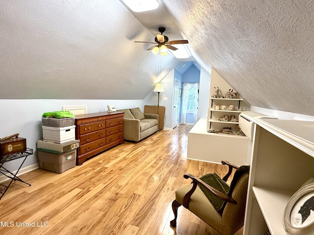 additional living space with a textured ceiling, light wood-style flooring, ceiling fan, vaulted ceiling, and baseboards