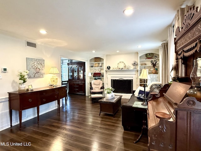 living room with dark wood-style flooring, built in shelves, recessed lighting, and a fireplace