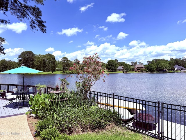 dock area featuring fence, outdoor dining area, and a deck with water view
