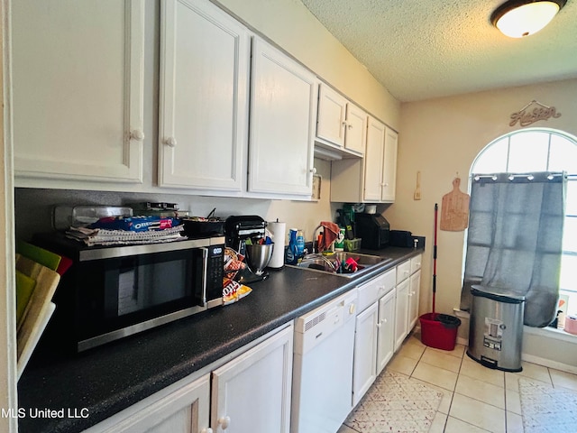 kitchen featuring white cabinetry, a textured ceiling, dishwasher, light tile patterned flooring, and sink